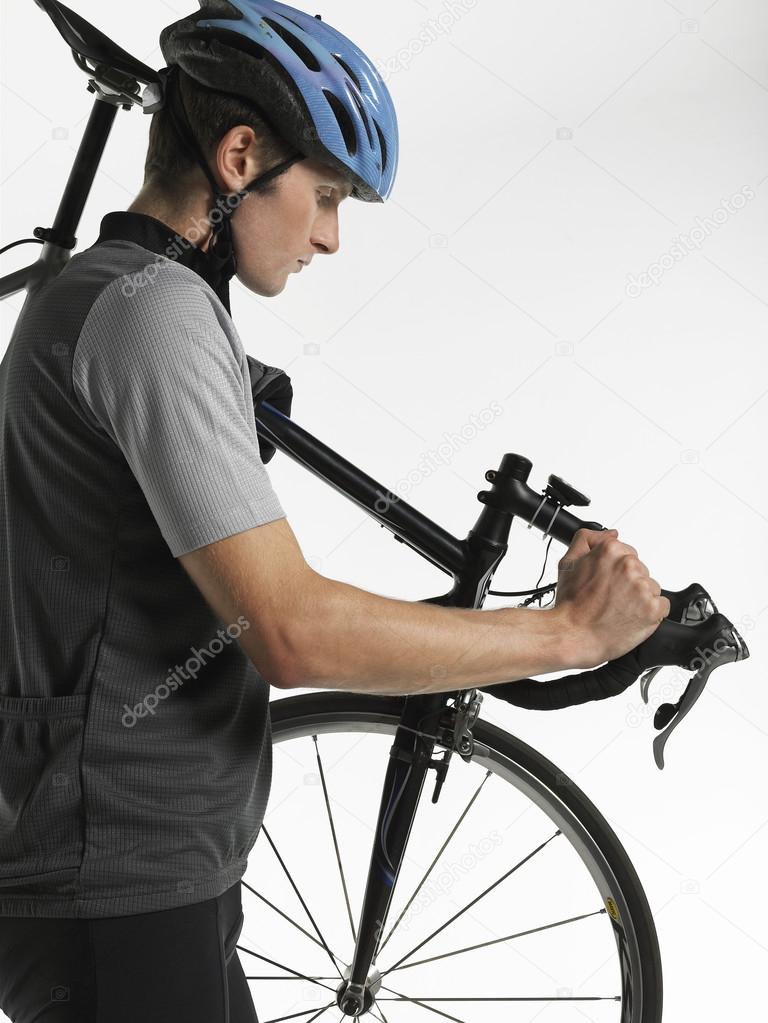 Male bicyclist carrying bicycle