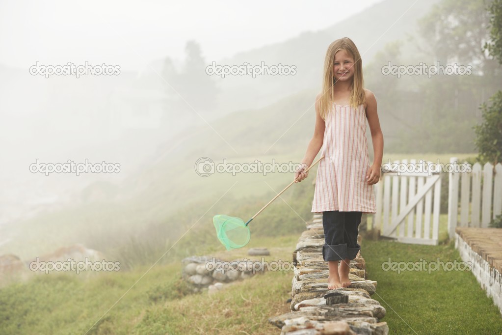 Girl Balancing with Butterfly Net on Wall