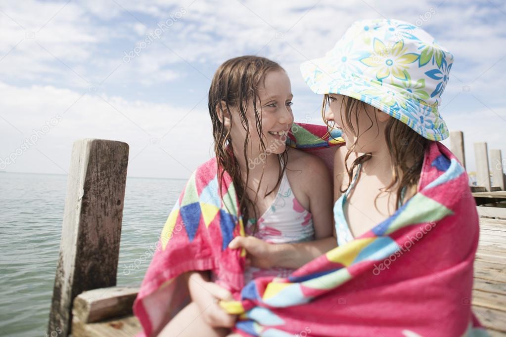 girls with in towel on wooden jetty 