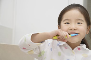 Girl in pyjamas Brushing Her Teeth clipart