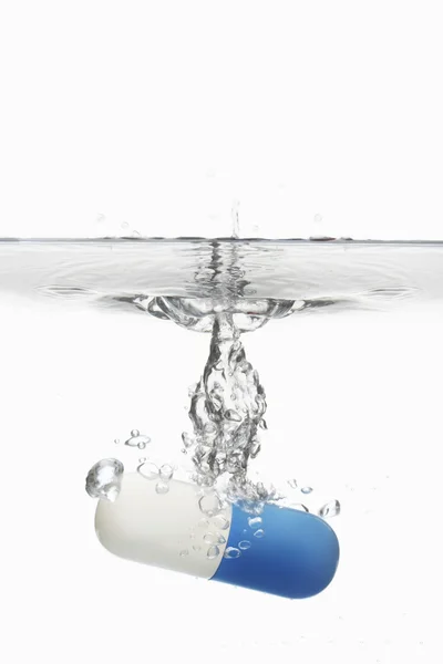 Capsule pill sinking in water — Stock Photo, Image