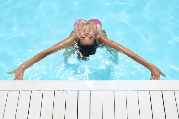 Mulher que se estende de volta na piscina — Fotografia de Stock