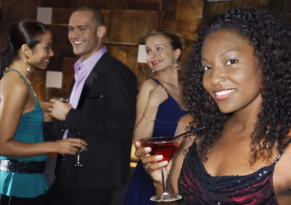 Woman holding cocktail standing in ba — Stock Photo, Image