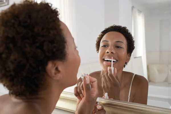 Mulher aplicando brilho labial no espelho — Fotografia de Stock