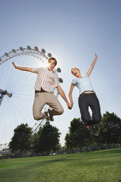 Couple jumping in front of London Eye — Stock Photo, Image