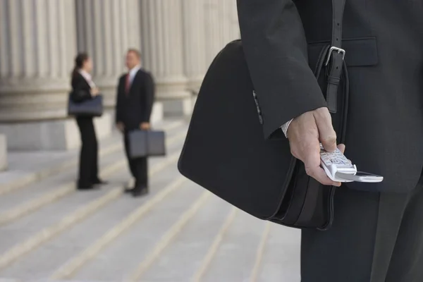 Бизнесмен, использующий мобильный телефон и людей, говорящих — стоковое фото