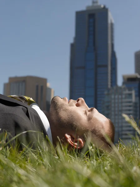 Zakenman liggen op gras — Stockfoto