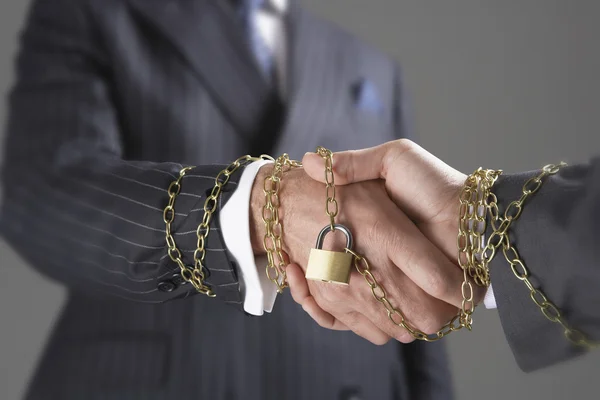 Shaking hands wrapped in chain with padlock — Stock Photo, Image