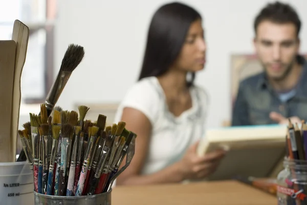 Multiethnic couple looking at canvases — Stock Photo, Image