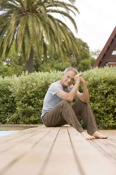 Hombre sentado junto a la piscina — Foto de Stock