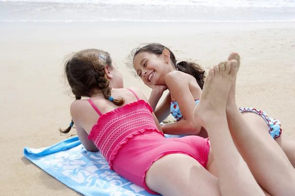 Pre-teen girls lying on beach — Stock Photo, Image