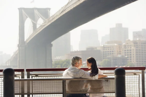 Пара отдыхающих на скамейке под Бруклинским мостом — стоковое фото