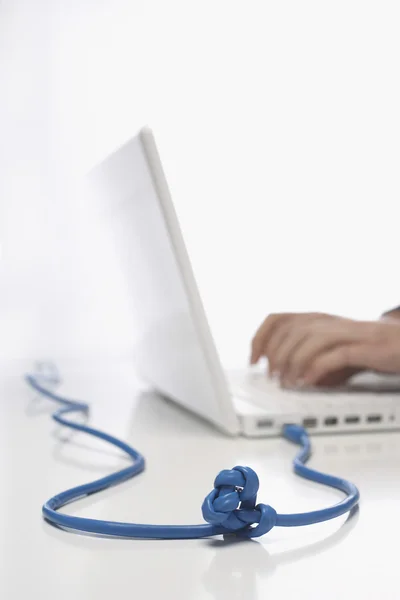 Kvinna med laptop med knuten kabel — Stockfoto