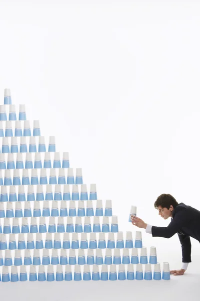 Hombre apilando vasos de plástico en una pirámide — Foto de Stock