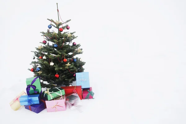 Kerstboom met presenteert in sneeuw — Stockfoto