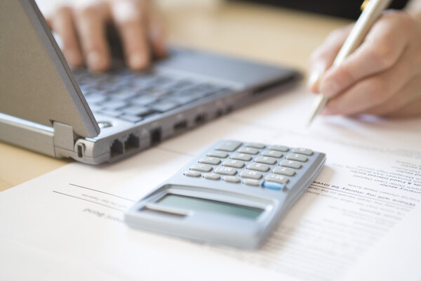Woman using laptop and calculator