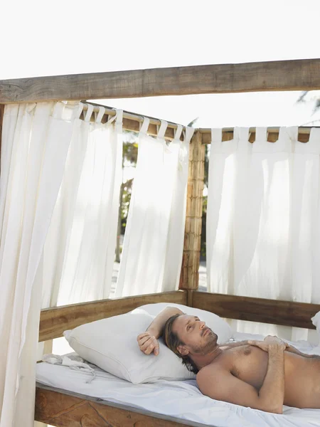 Man lying on four poster bed — Stock Photo, Image