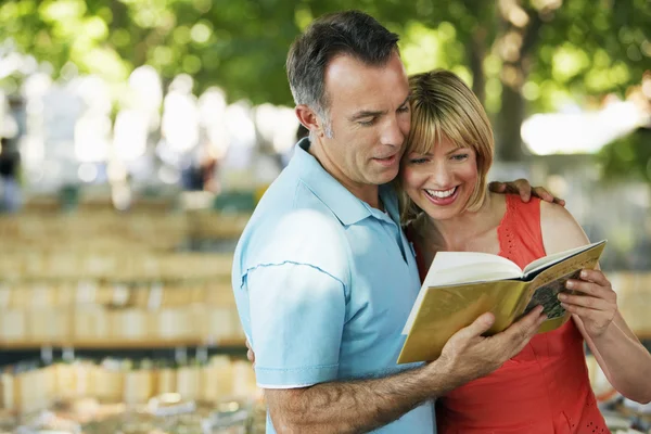 Couple in park looking at book — Stock Photo, Image