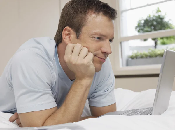 Mann benutzt Laptop auf Bett — Stockfoto