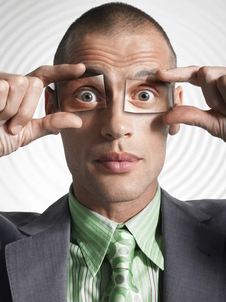 Businessman holding photos of eyes — Stock Photo, Image