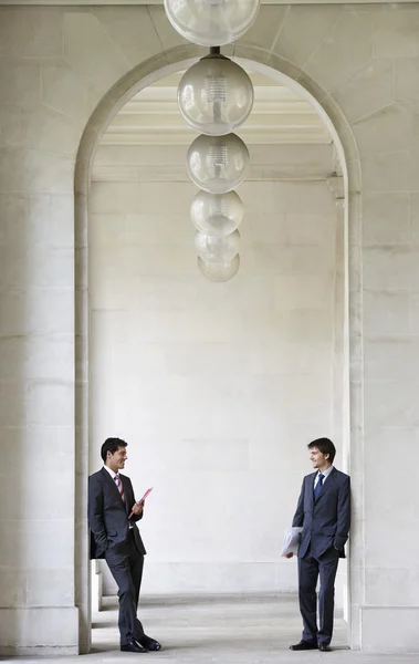 Businessmen in archway talking — Stock Photo, Image