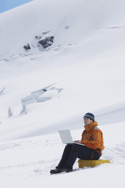 Hiker using laptop on mountain