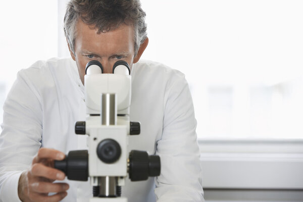Male lab worker adjusting microscope