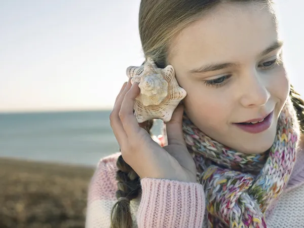 Chica escuchando a una concha marina —  Fotos de Stock