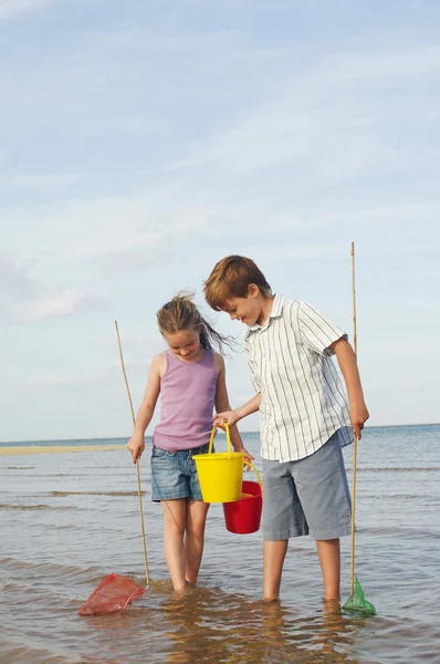 弟弟和妹妹用水桶和渔网袜 — 图库照片