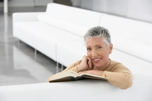 Femme avec livre sur canapé — Photo