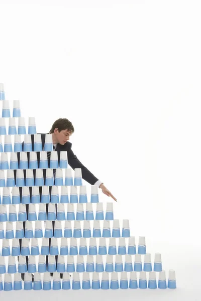 Hombre apilando vasos de plástico en la pirámide — Foto de Stock