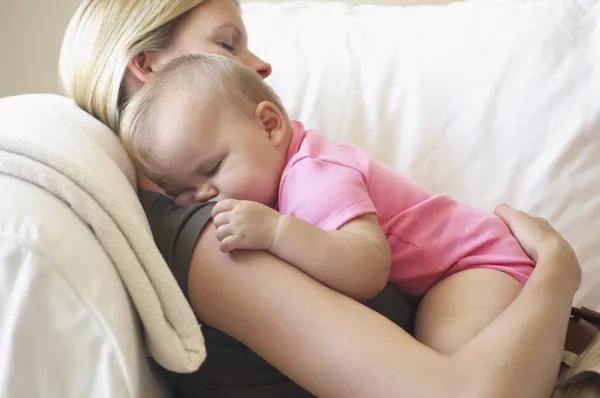 Kanepede uyuyan bebek ile anne — Stok fotoğraf