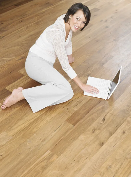 Lachende jonge vrouw met behulp van laptop — Stockfoto