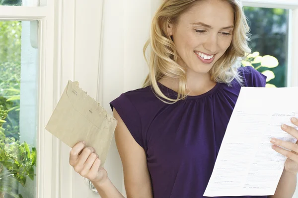Frau schaut auf Brief und sieht glücklich aus — Stockfoto