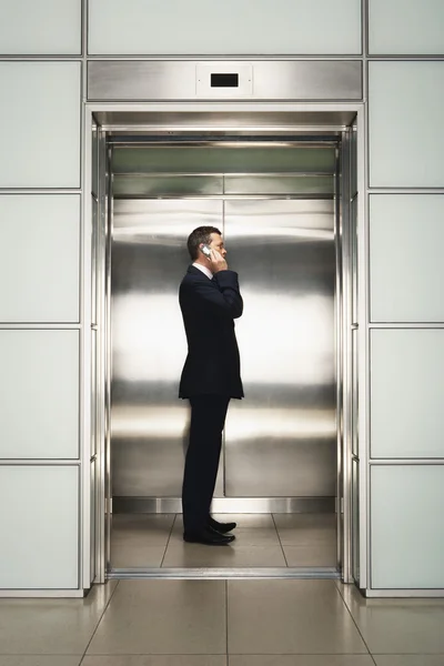 Бизнесмен с мобильным телефоном в лифте — стоковое фото