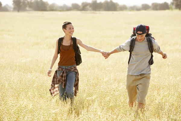 Hiking couple walking through field — Stock Photo, Image