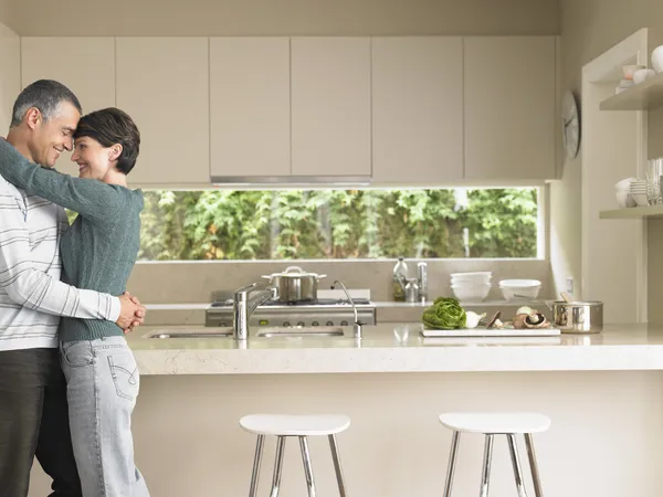 Uomo e donna abbracciati in cucina — Foto Stock