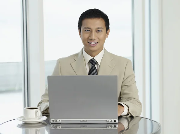 Бизнесмен сидит за столом и работает над ноутбуком — стоковое фото