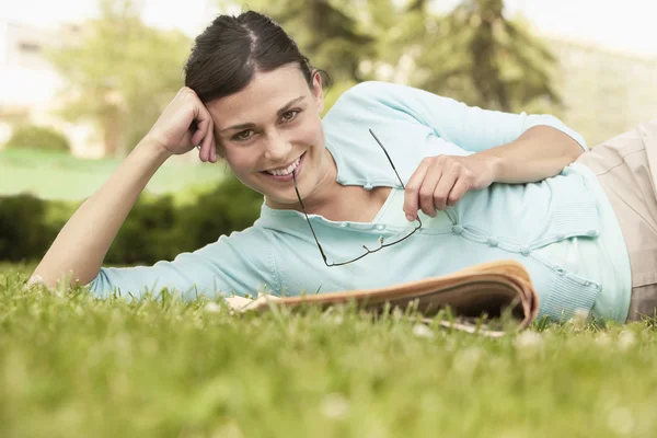 Woman lying on grass with newspaper — Stock Photo, Image