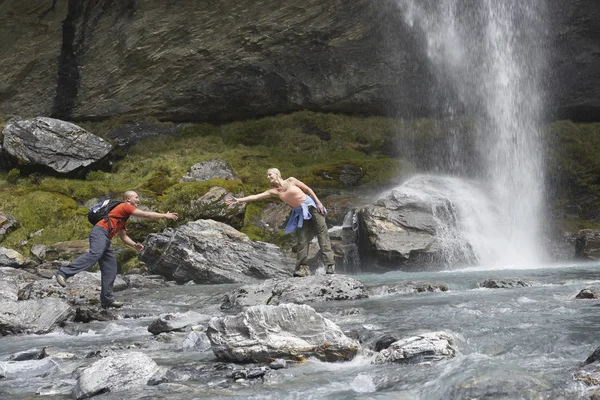 Hikers under waterfall — Stock Photo, Image