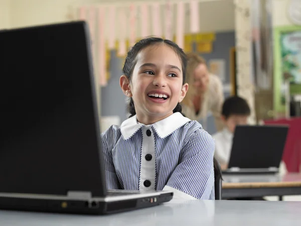 Elementary schoolgirl using laptop — Stock Photo, Image