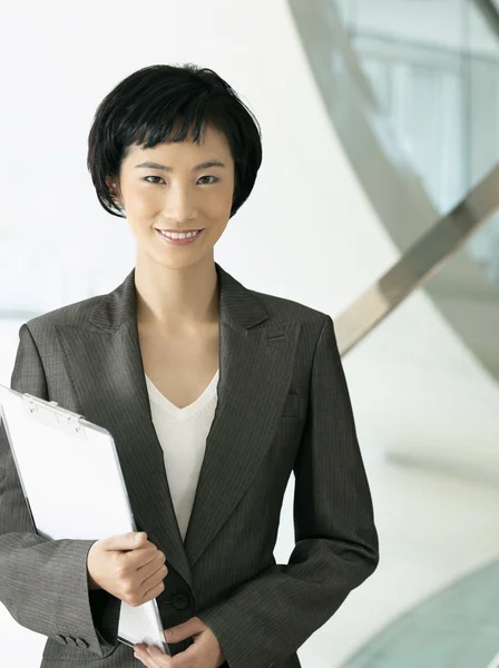 Smiling businesswoman holding clipboard — Stock Photo, Image