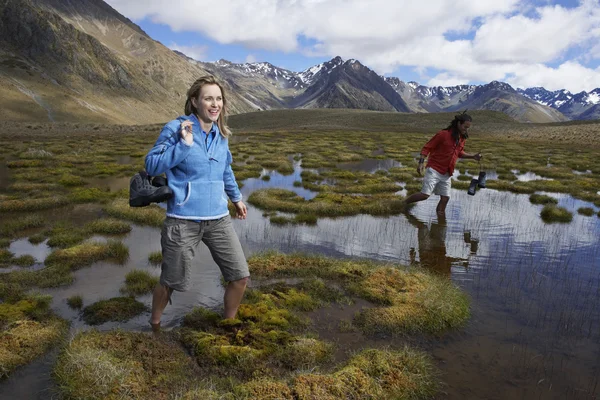 Two hikers wading through pond — Stock Photo, Image