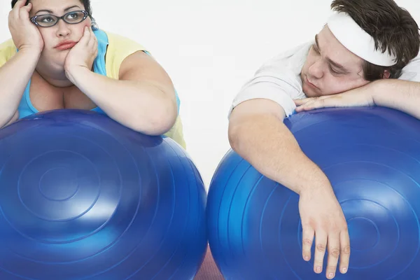 Uomo e donna sdraiati sulle palle di esercizio — Foto Stock