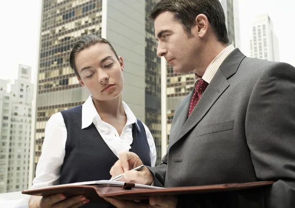 Business man showing paperwork to business woman — Stock Photo, Image
