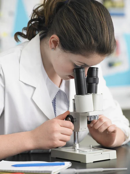 Kvinnliga gymnasiestudent med Mikroskop — Stockfoto