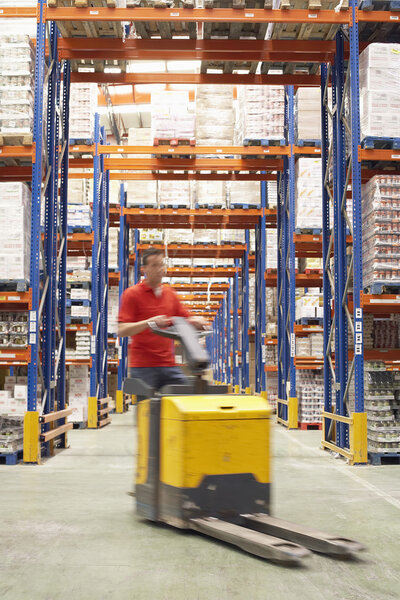 Man Driving Pallet Jack Through Warehouse
