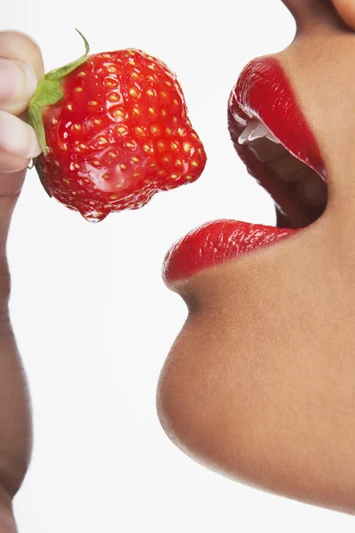 Жінка з червоними губами кусає полуницю — стокове фото