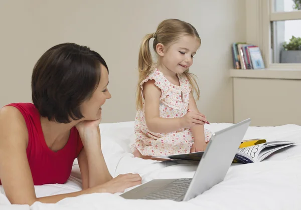 Madre e figlia disegno e utilizzando il computer portatile — Foto Stock