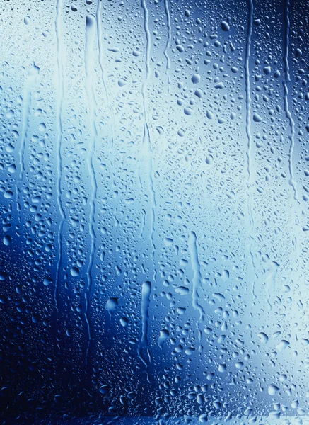 Gotas de agua corriendo por el cristal azul — Foto de Stock